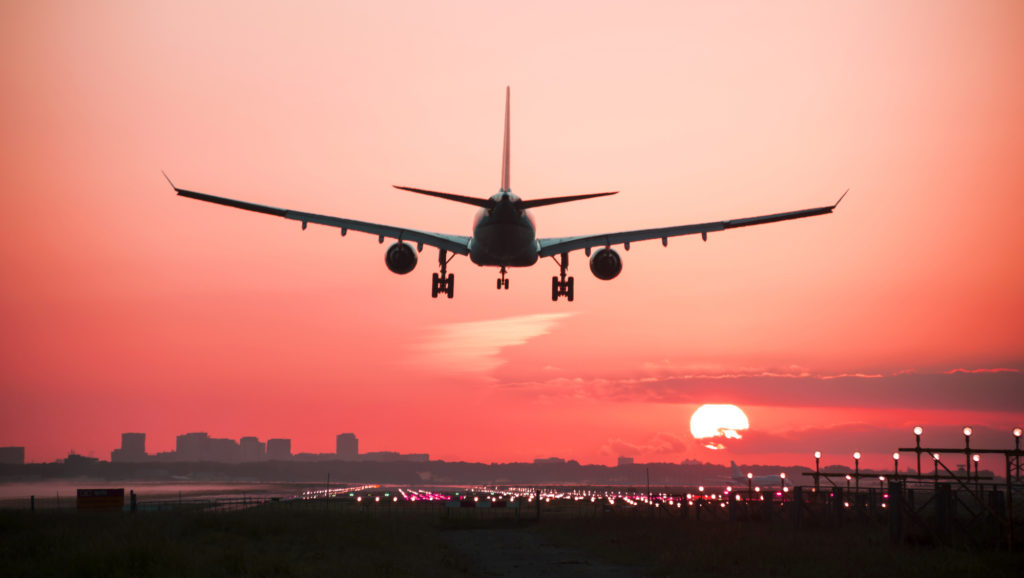 An airplane landing with a beautiful sunset