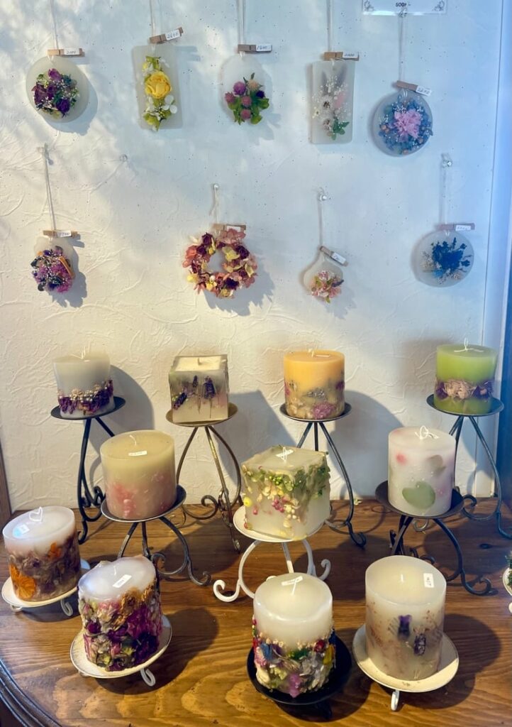 A display of candles on a table with flowers on them.