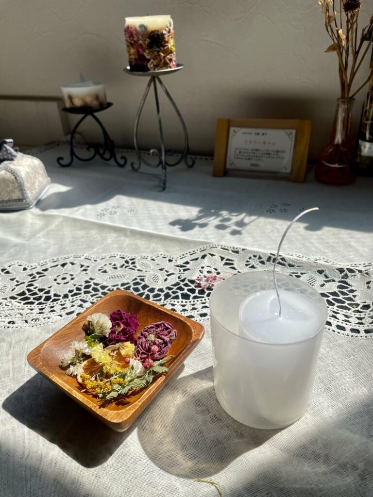 A bowl of flowers and a candle on a table.