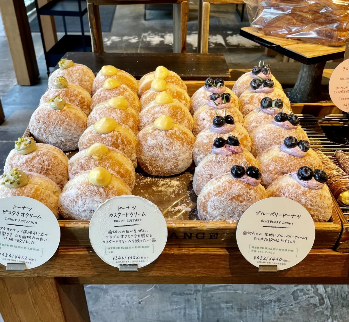 A display of cream-filled doughnuts topped with berries and dusted with powdered sugar on a tray in a Fukuoka bakery.