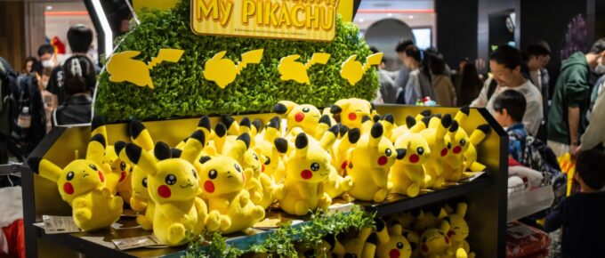 A store display filled with multiple Pikachu plush toys, with a sign reading "My Pikachu," and people browsing in the background.